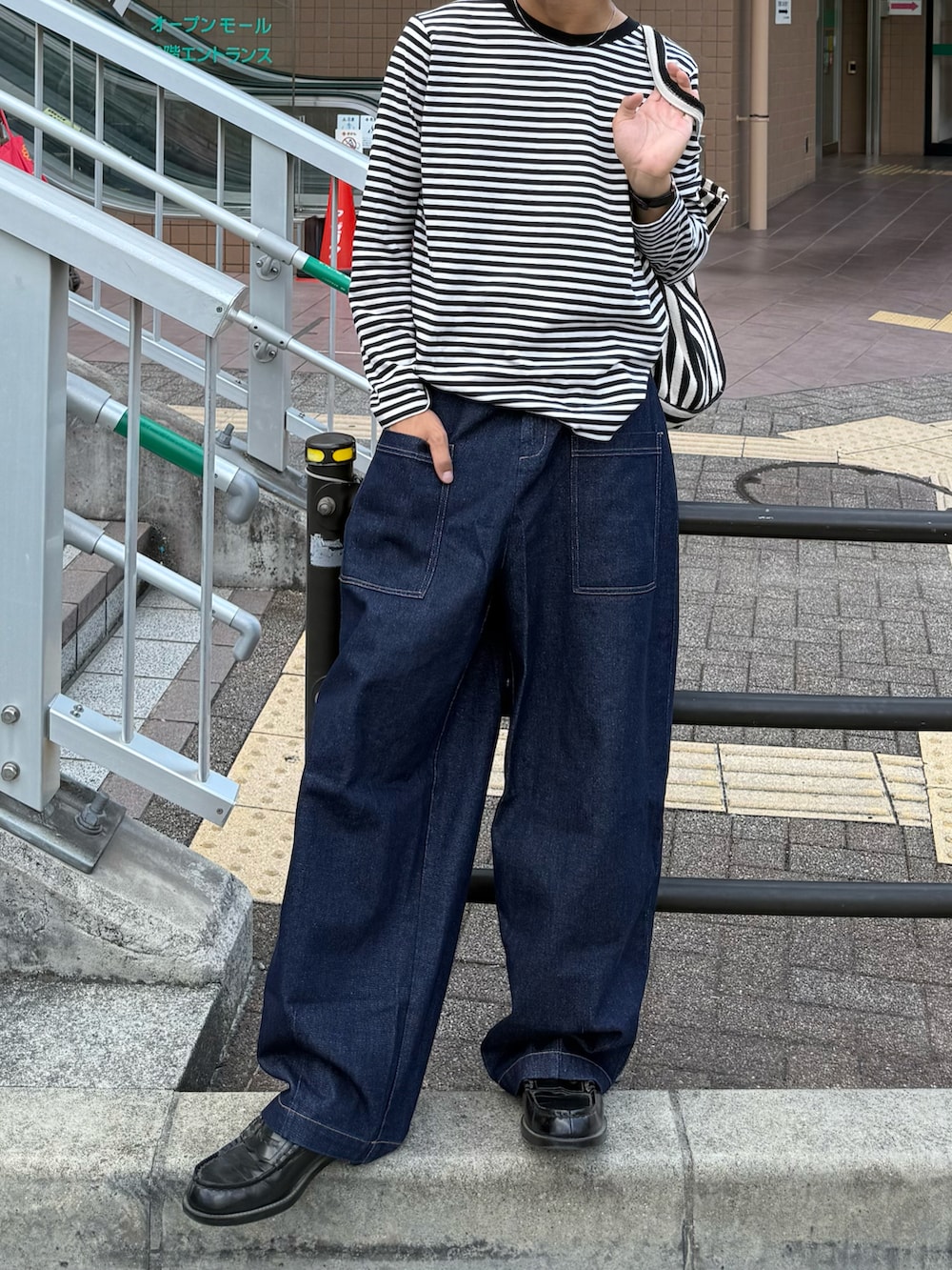 ブラック系のトートバッグ、ブラック系のTシャツ/カットソー、ブルー系のデニムパンツを着用したメンズの秋コーディネートの2枚目の写真