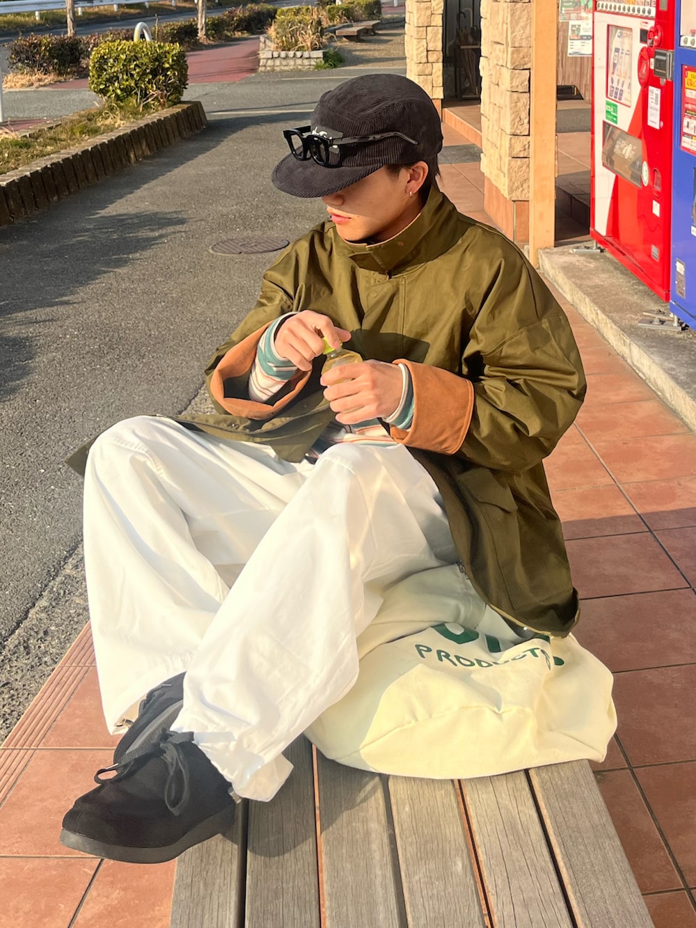 ホワイト系のパンツ、ブラック系のモカシン/デッキシューズ、グリーン系のカバーオールを着用したメンズの春コーディネートの3枚目の写真