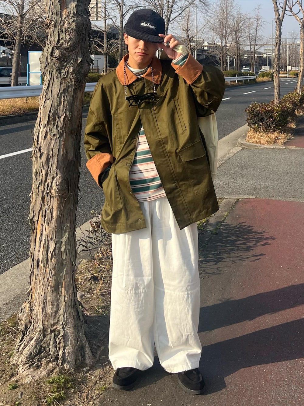 ホワイト系のパンツ、ブラック系のモカシン/デッキシューズ、グリーン系のカバーオールを着用したメンズの春コーディネートの2枚目の写真