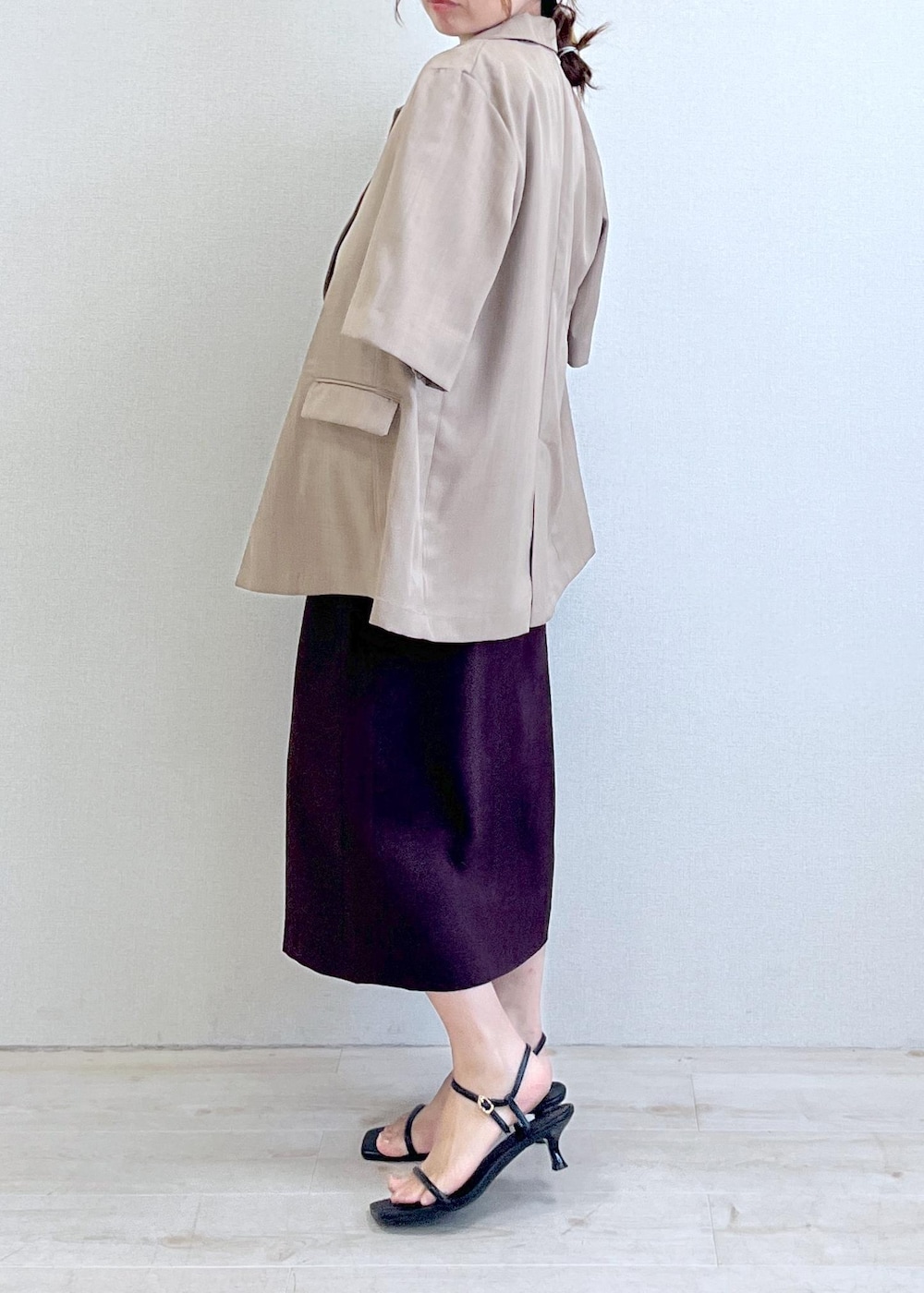 ブラック系のサンダル、ホワイト系のTシャツ/カットソー、ブラウン系のスカートを着用したレディースの夏コーディネートの2枚目の写真