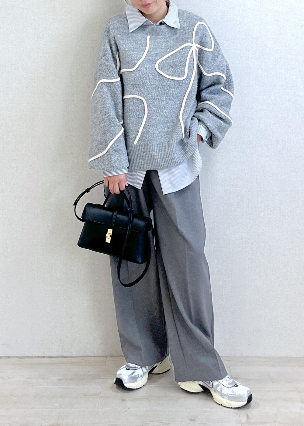グレー系のニット/セーター、グレー系のスラックス、ブラック系のショルダーバッグを着用したレディースの冬コーディネートの5枚目の写真