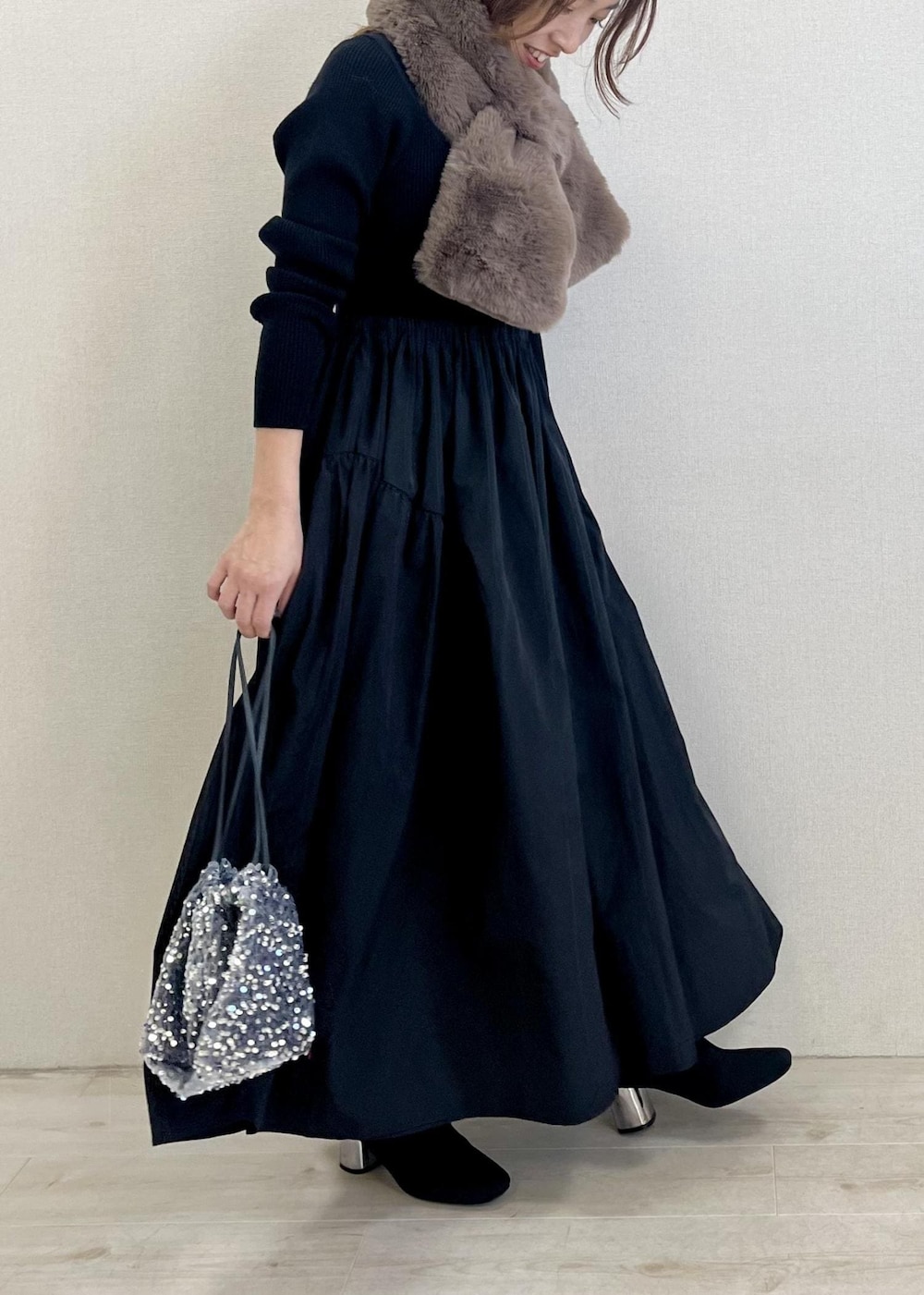 ブラック系のブーツ、シルバー系のハンドバッグ、ブラック系のワンピースを着用したレディースの冬コーディネートの2枚目の写真