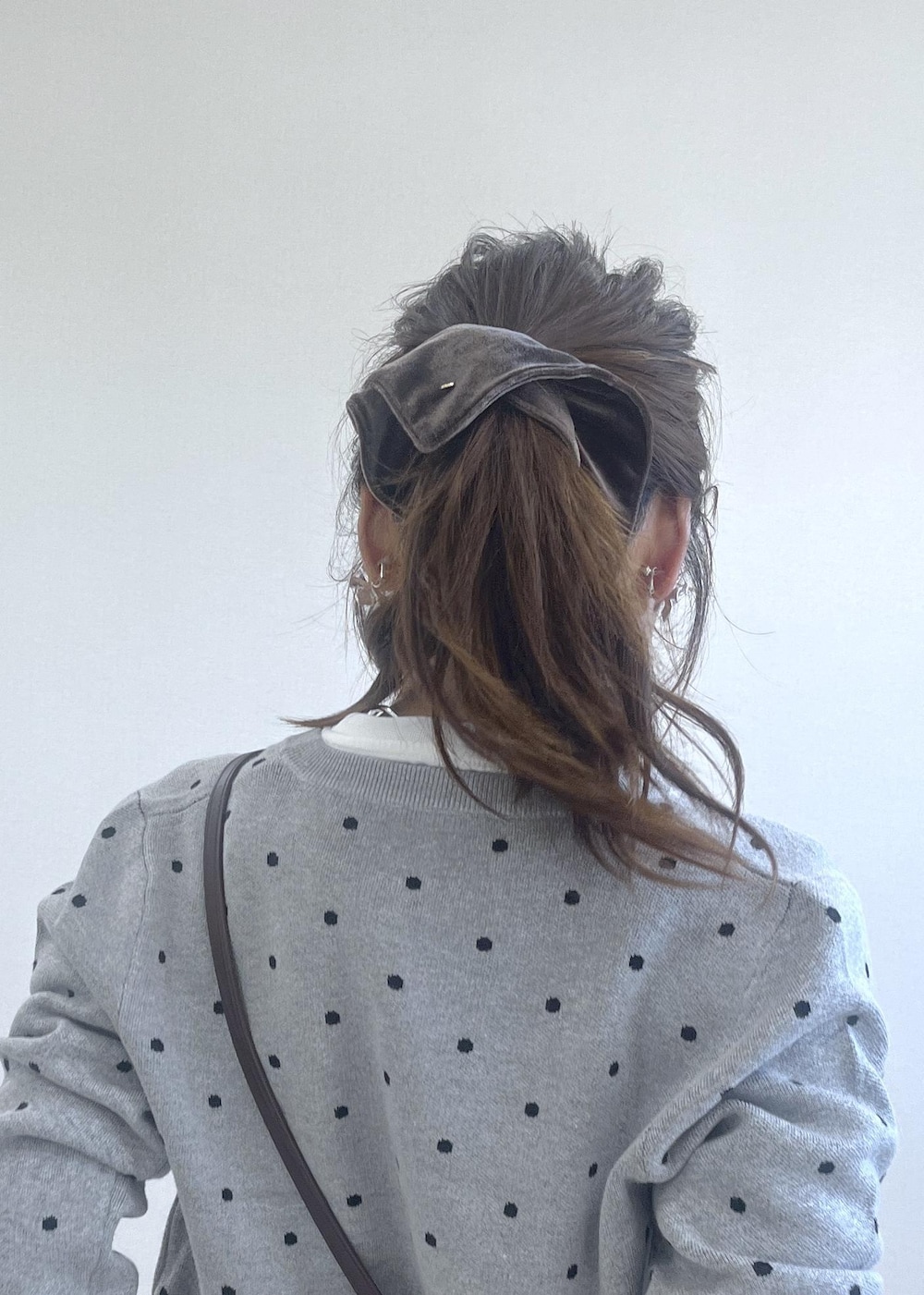 ブラウン系のショルダーバッグ、ブラック系のブーツ、ブラック系のスカートを着用したレディースの秋コーディネートの7枚目の写真