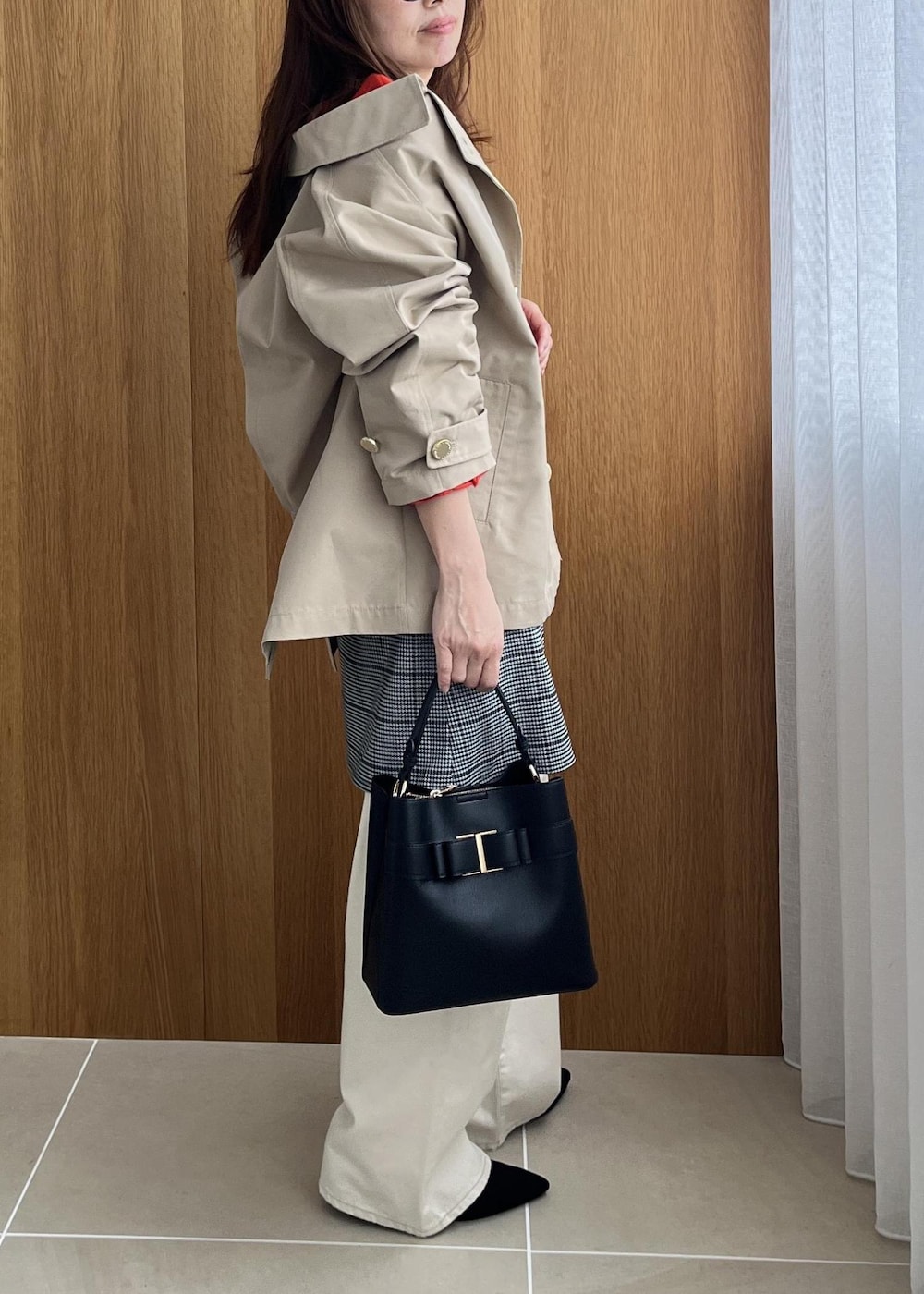 ブラック系のショルダーバッグ、ベージュ系のトレンチコート、ホワイト系のデニムパンツを着用したレディースの秋コーディネートの9枚目の写真