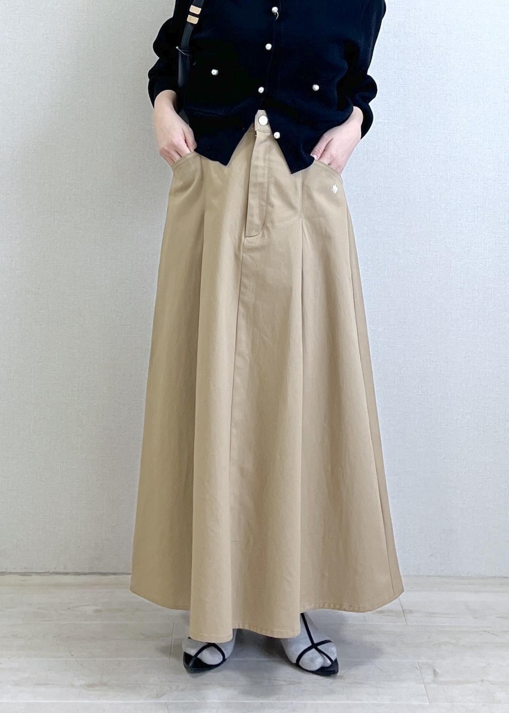 ブラック系のショルダーバッグ、ブラック系のカーディガン/ボレロ、ベージュ系のスカートを着用したレディースの春コーディネートの2枚目の写真