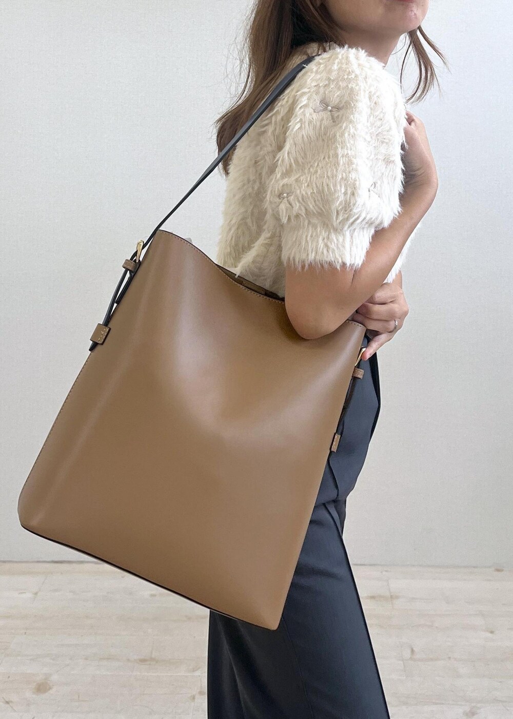 シルバー系のパンプス、イエロー系のショルダーバッグ、ホワイト系のニット/セーターを着用したレディースの秋コーディネートの6枚目の写真