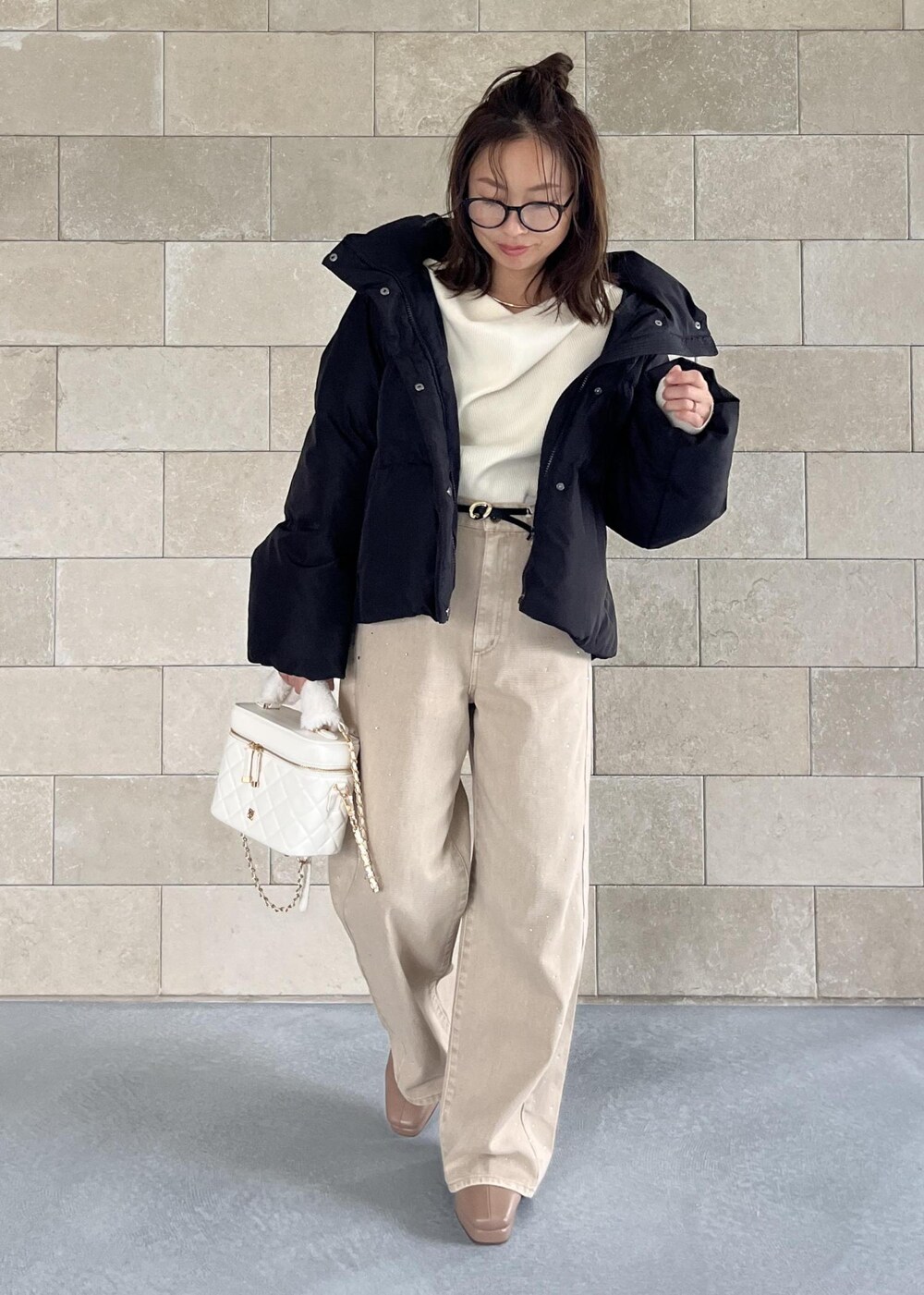 ブラック系のダウンジャケット/コート、ベージュ系のブーツ、ホワイト系のハンドバッグを着用したレディースの秋コーディネートの9枚目の写真