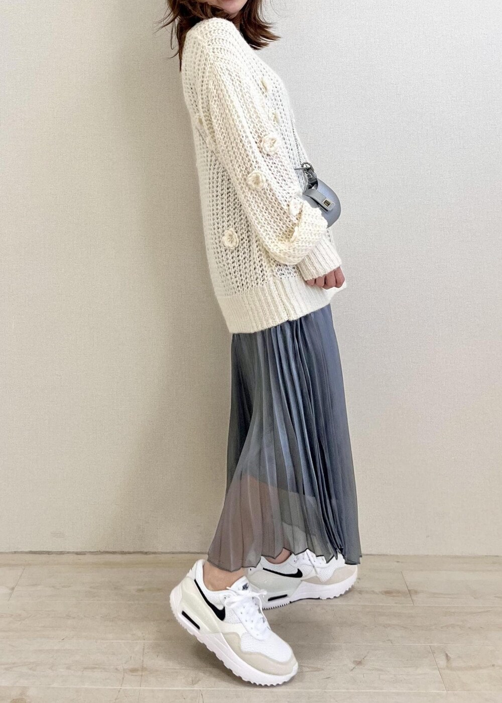 ホワイト系のニット/セーター、シルバー系のスカートを着用したレディースの冬コーディネートの2枚目の写真