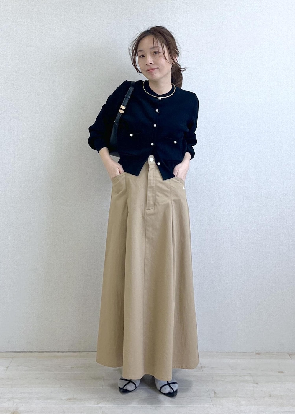 ブラック系のショルダーバッグ、ブラック系のカーディガン/ボレロ、ベージュ系のスカートを着用したレディースの春コーディネートの9枚目の写真