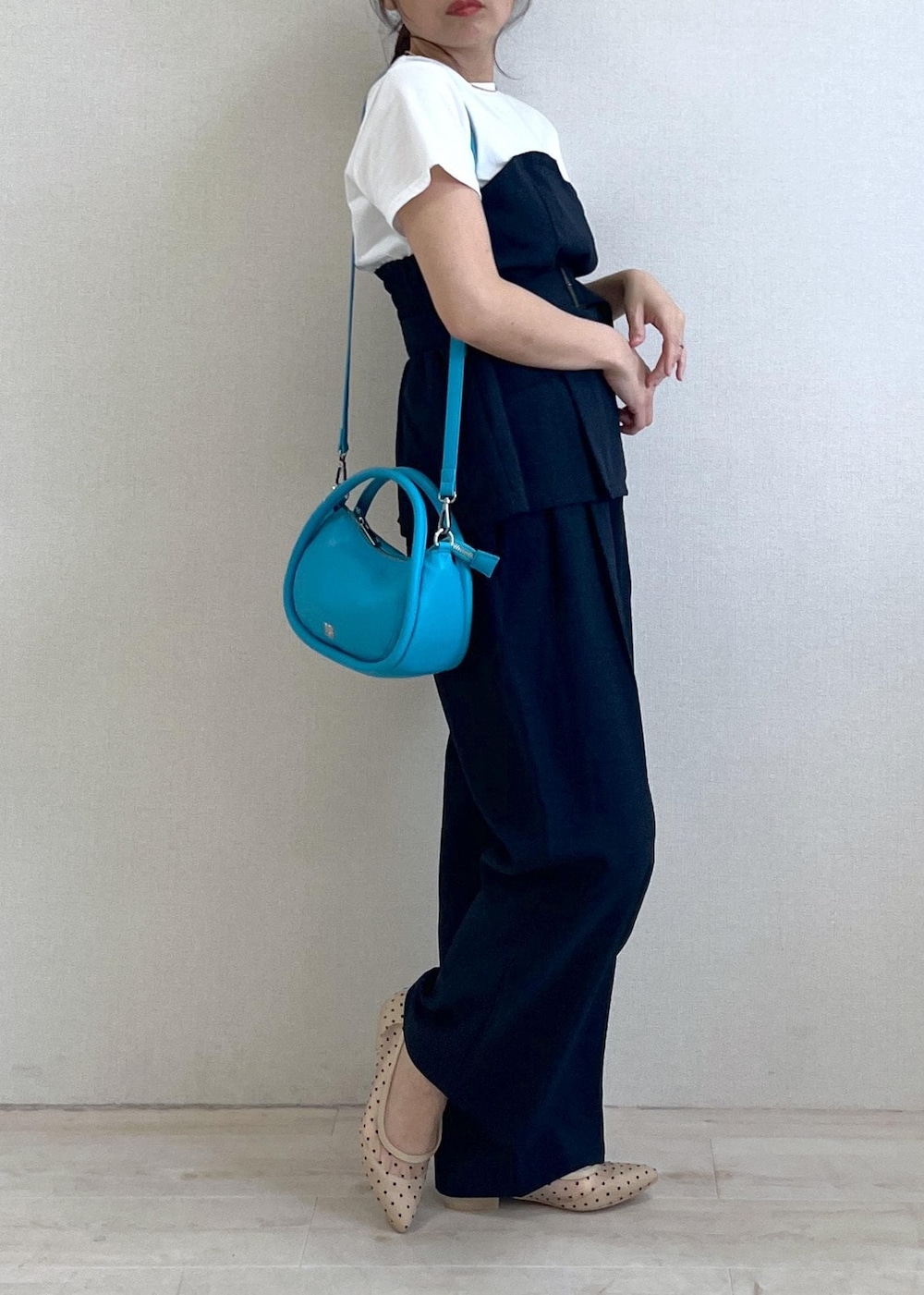 ブルー系のスラックス、ベージュ系のパンプス、ブルー系のショルダーバッグを着用したレディースの春コーディネートの2枚目の写真