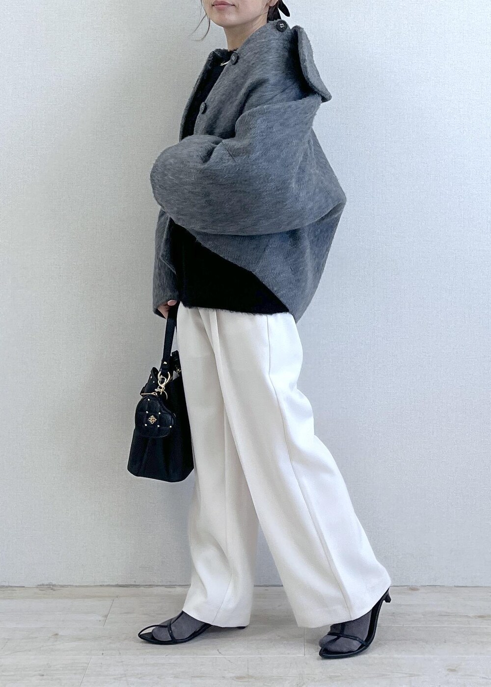 グレー系のブルゾン、ホワイト系のスラックス、ブラック系のニット/セーターを着用したレディースの冬コーディネートの2枚目の写真