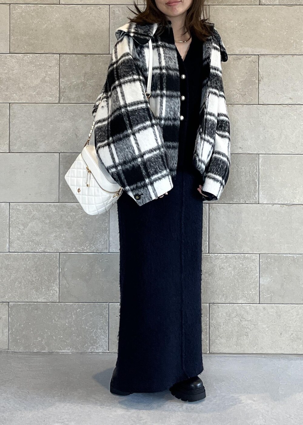 ブラック系のブーツ、ホワイト系のハンドバッグ、ブルー系のスカートを着用したレディースの秋コーディネートの2枚目の写真