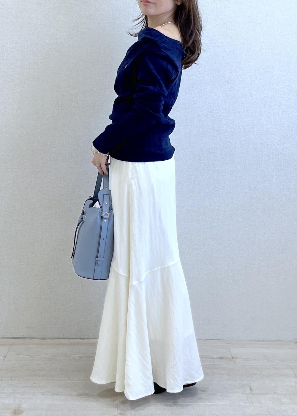 ブラック系のパンプス、ブルー系のショルダーバッグ、ベージュ系のトレンチコートを着用したレディースの春コーディネートの2枚目の写真