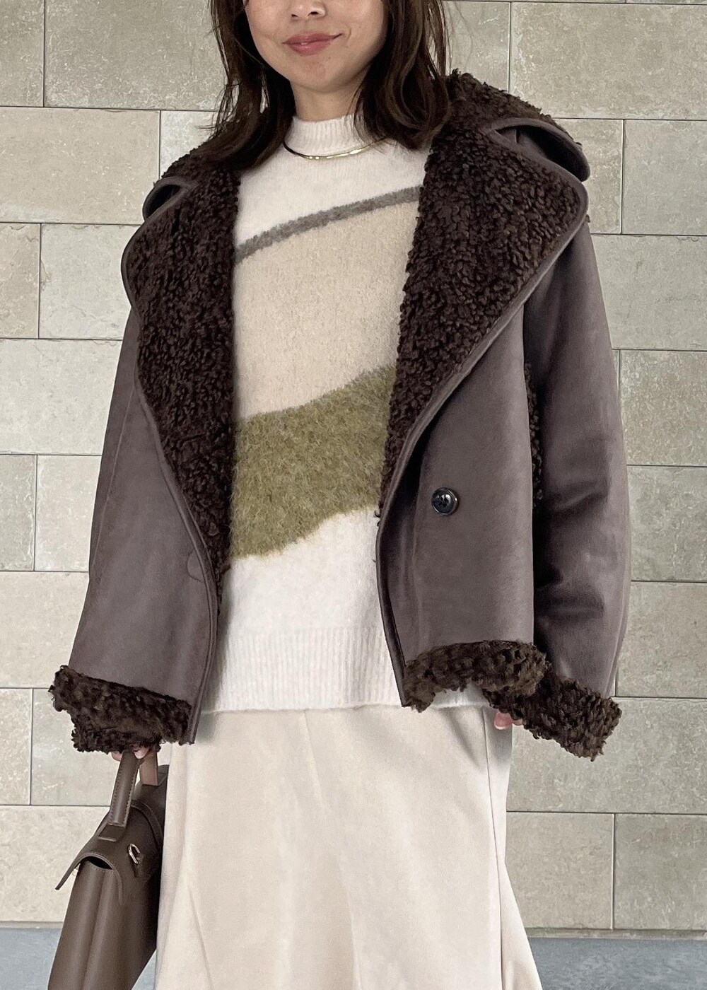 ベージュ系のショルダーバッグ、ブラック系のブーツ、ブラウン系のブルゾンを着用したレディースの秋コーディネートの6枚目の写真