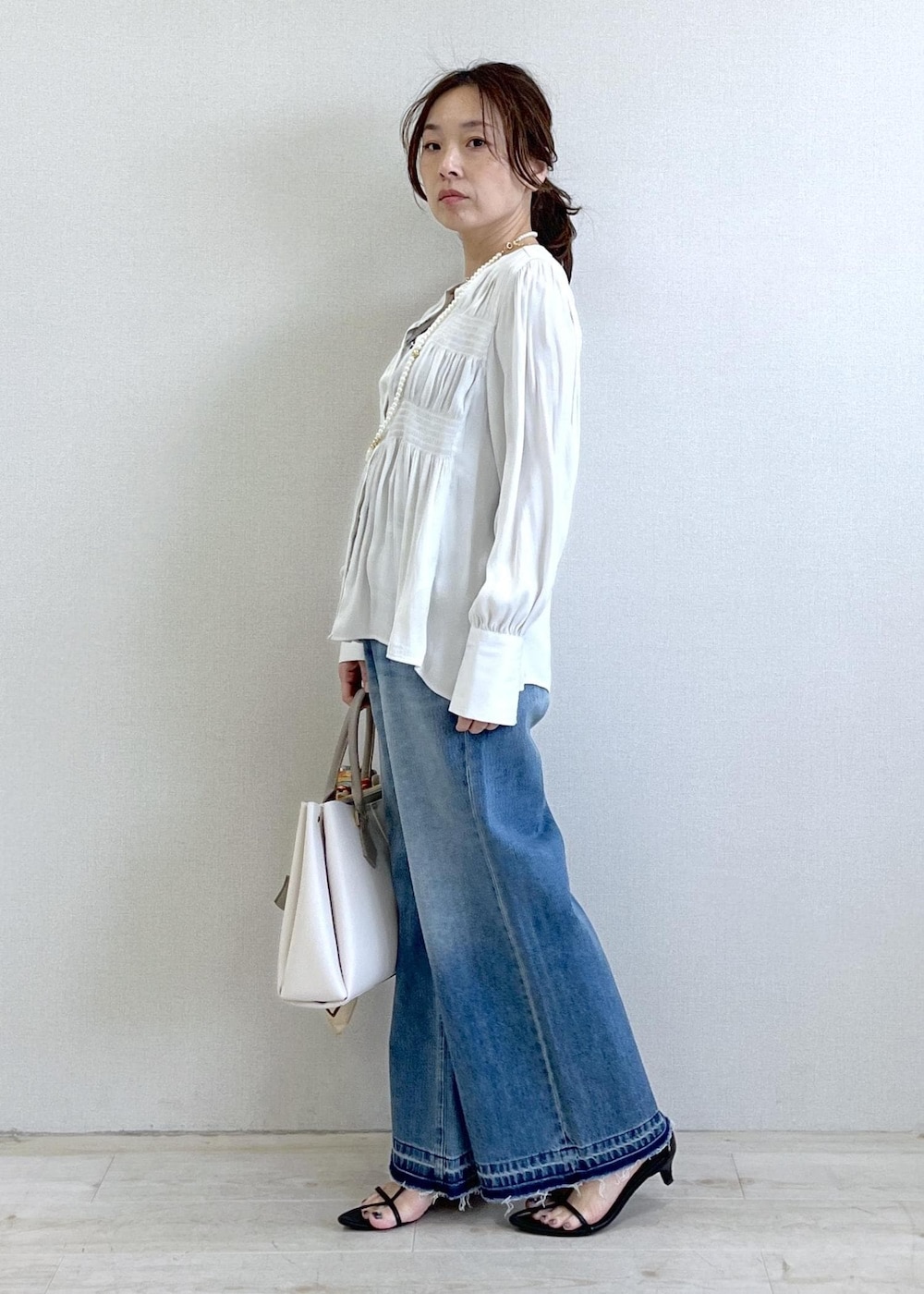 ブラック系のキャミソール、ブルー系のデニムパンツ、ブラック系のカーディガン/ボレロを着用したレディースの春コーディネートの8枚目の写真