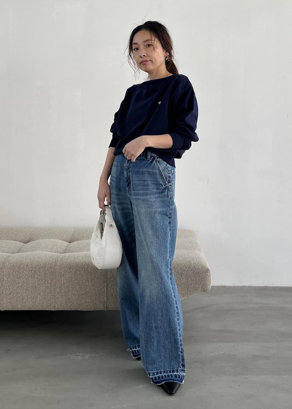 ホワイト系のハンドバッグ、ブラック系のパンプス、ブルー系のデニムパンツを着用したレディースの冬コーディネートの8枚目の写真