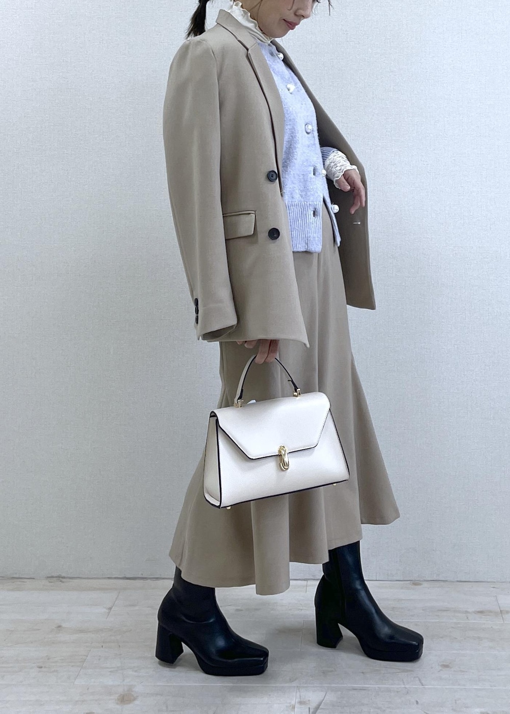 ブラック系のブーツ、ベージュ系のスカート、パープル系のカーディガン/ボレロを着用したレディースの秋コーディネートの4枚目の写真