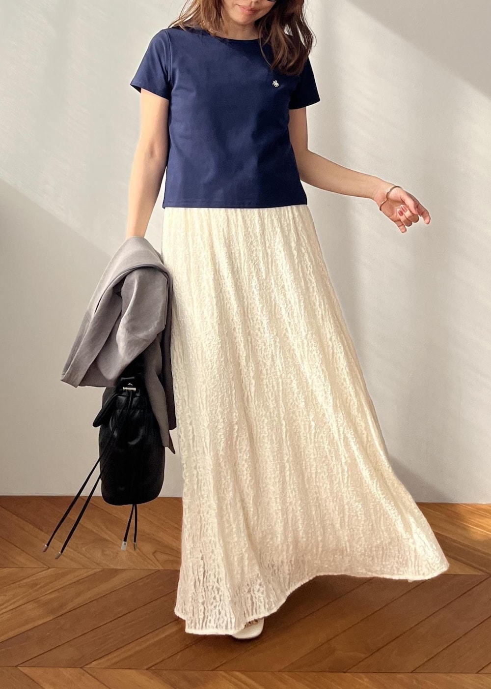 ホワイト系のスカート、ブラック系のショルダーバッグ、ホワイト系のサンダルを着用したレディースの春コーディネートの7枚目の写真