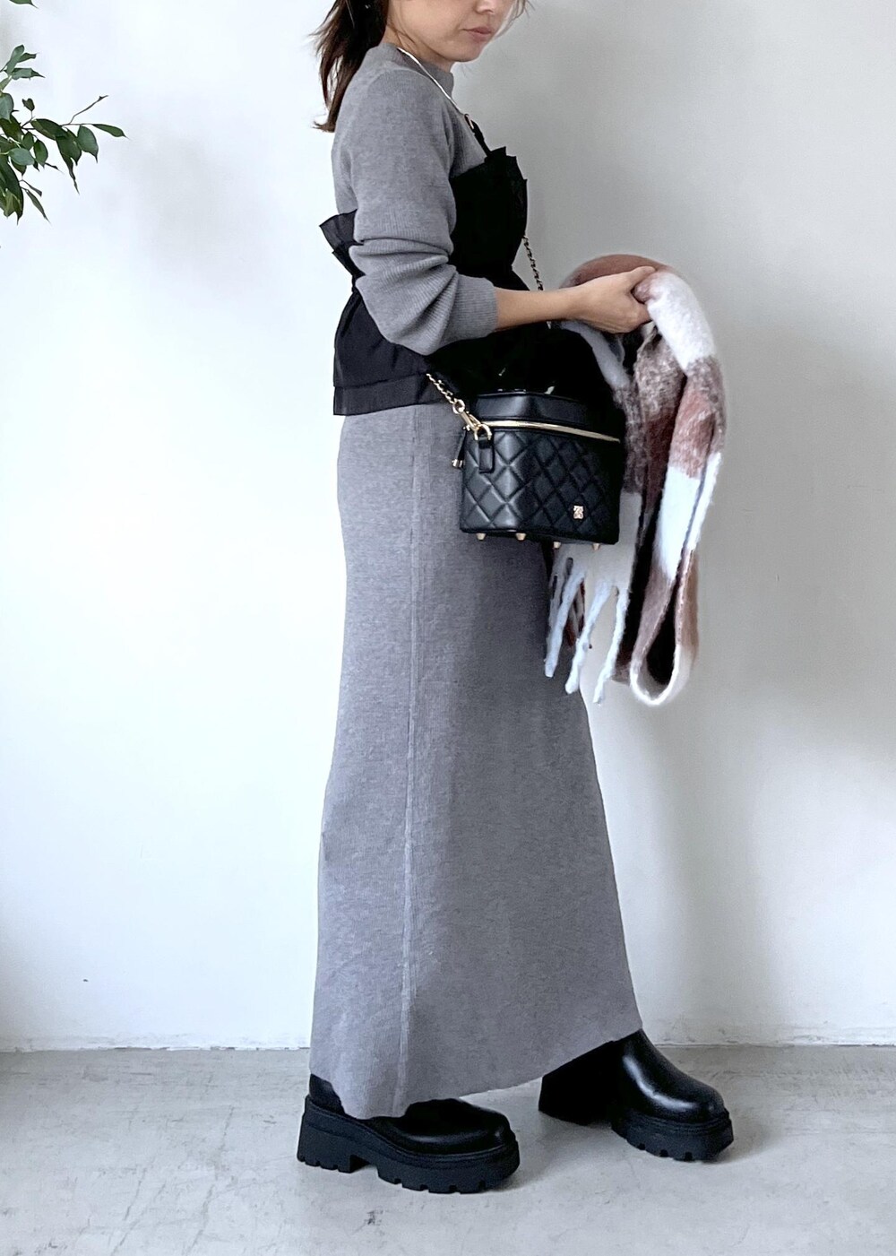 ブラック系のブーツ、グレー系のスカート、グレー系のニット/セーターを着用したレディースの秋コーディネートの3枚目の写真