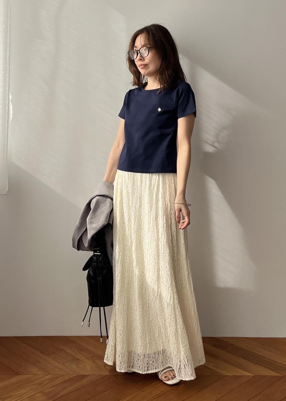 ホワイト系のスカート、ブラック系のショルダーバッグ、ホワイト系のサンダルを着用したレディースの春コーディネートの6枚目の写真