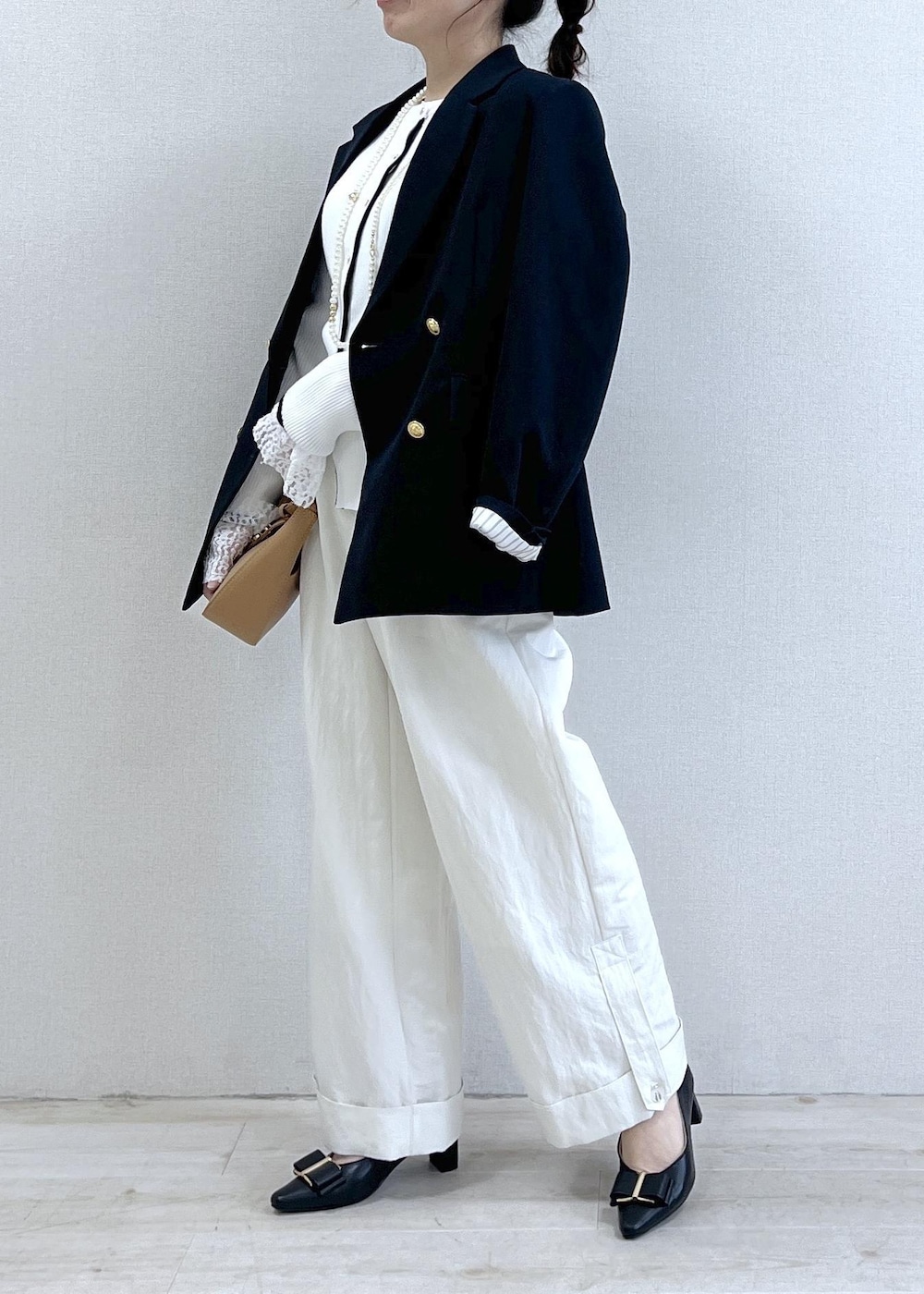 ブラック系のパンプス、ブルー系のテーラードジャケット、イエロー系のショルダーバッグを着用したレディースの冬コーディネートの3枚目の写真