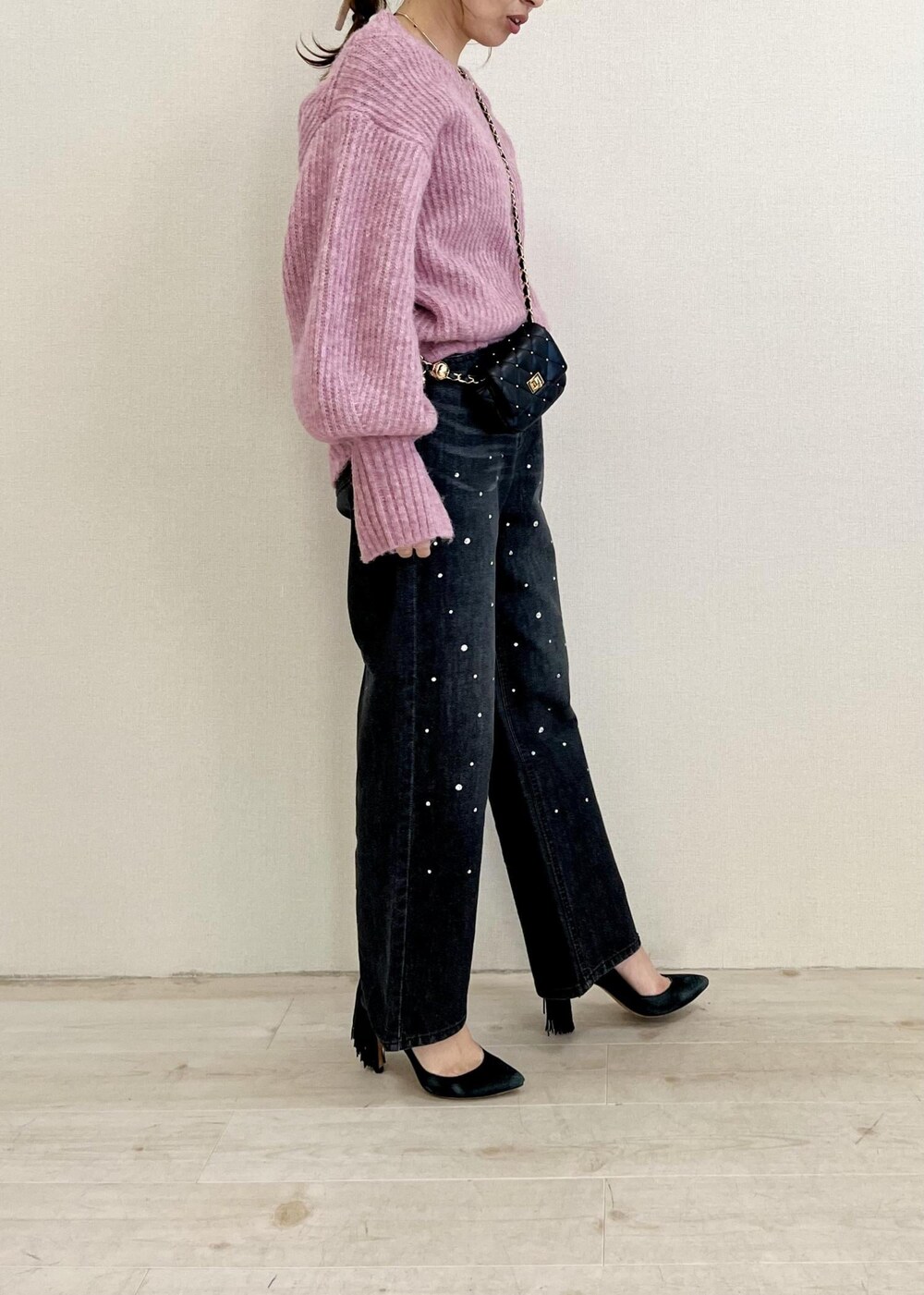 ブラック系のデニムパンツ、ブラック系のショルダーバッグ、ピンク系のニット/セーターを着用したレディースの冬コーディネートの2枚目の写真