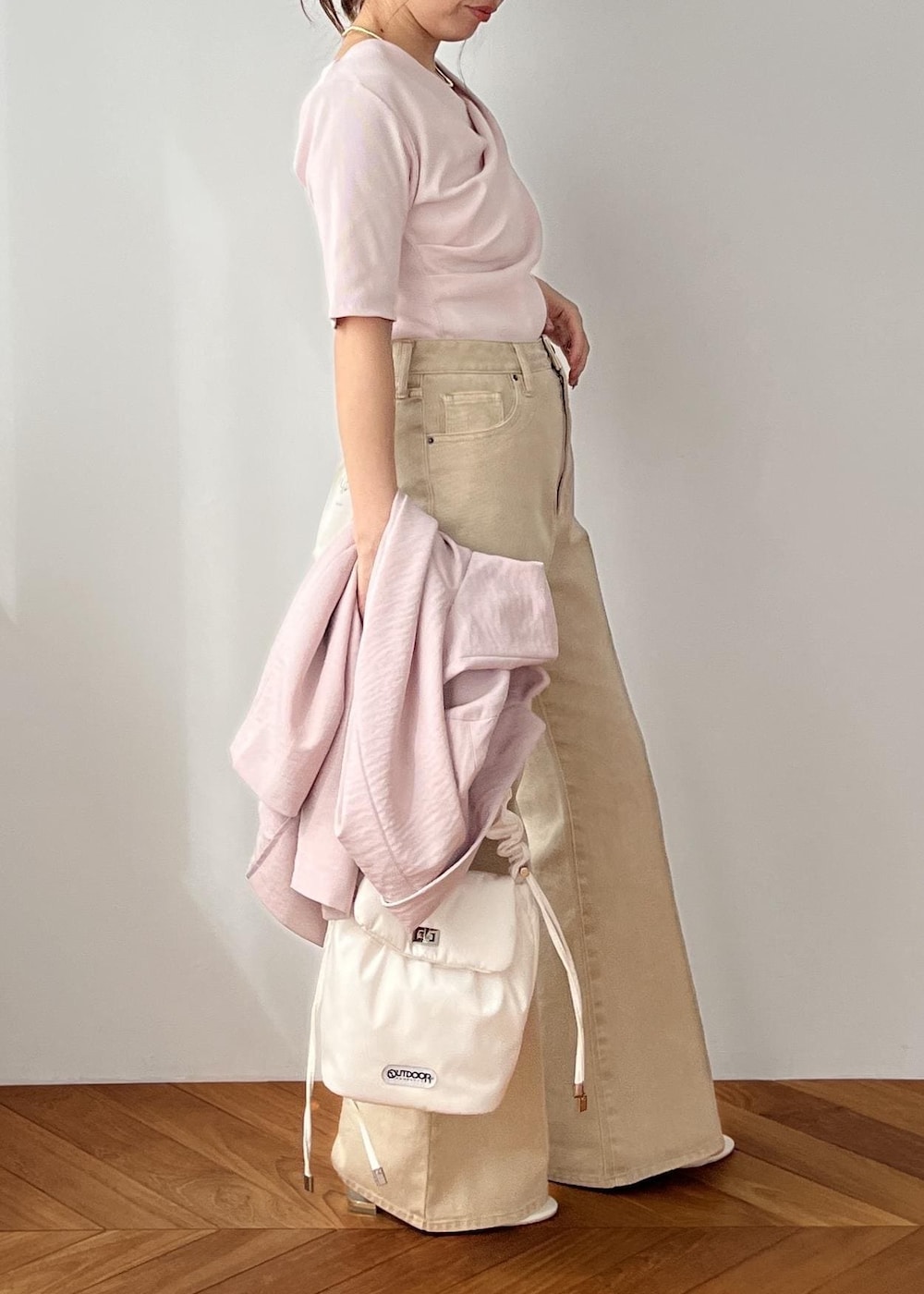 ホワイト系のショルダーバッグ、ピンク系のテーラードジャケット、ベージュ系のデニムパンツを着用したレディースの春コーディネートの2枚目の写真