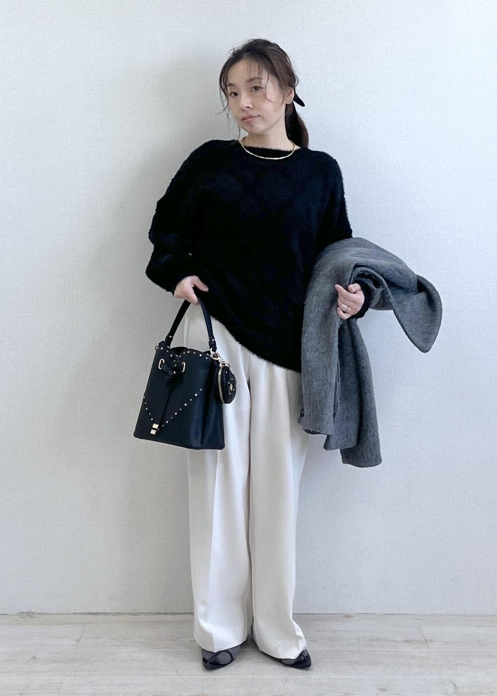 グレー系のブルゾン、ホワイト系のスラックス、ブラック系のニット/セーターを着用したレディースの冬コーディネートの7枚目の写真