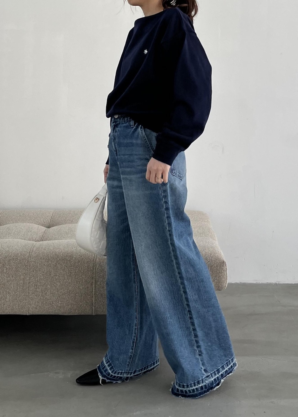 ホワイト系のハンドバッグ、ブラック系のパンプス、ブルー系のデニムパンツを着用したレディースの冬コーディネートの4枚目の写真