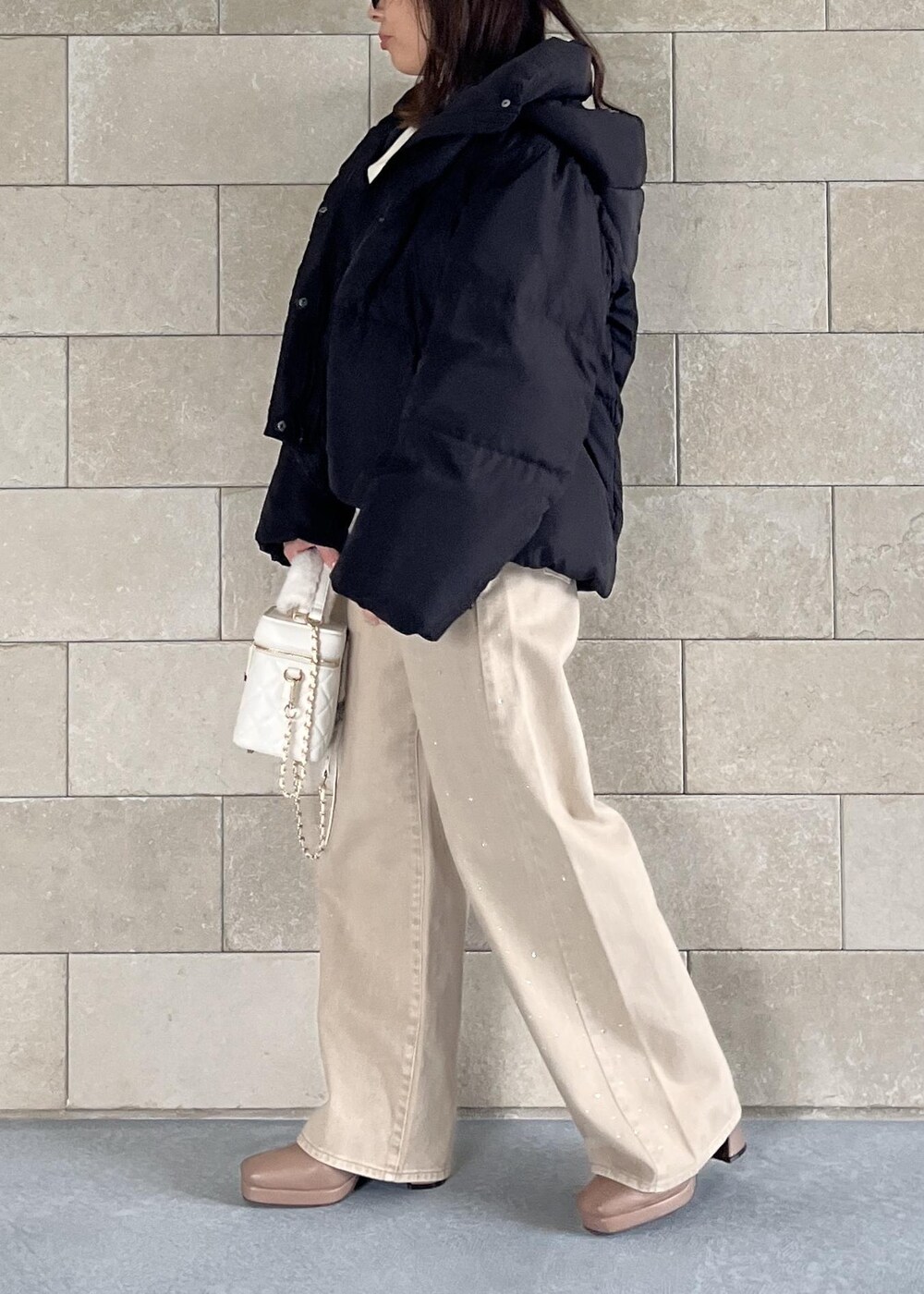 ブラック系のダウンジャケット/コート、ベージュ系のブーツ、ホワイト系のハンドバッグを着用したレディースの秋コーディネートの5枚目の写真