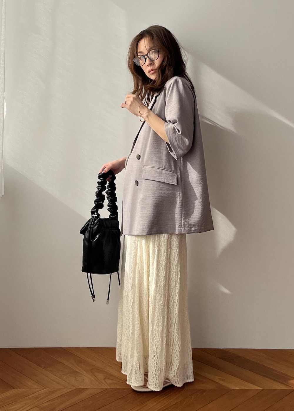 ホワイト系のスカート、ブラック系のショルダーバッグ、ホワイト系のサンダルを着用したレディースの春コーディネートの5枚目の写真