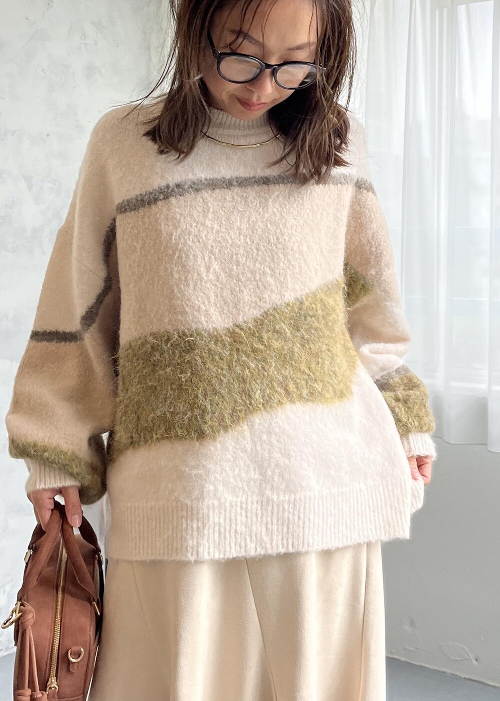 ブラウン系のボストンバッグ、ブラック系のブーツ、ホワイト系のスカートを着用したレディースの秋コーディネートの6枚目の写真