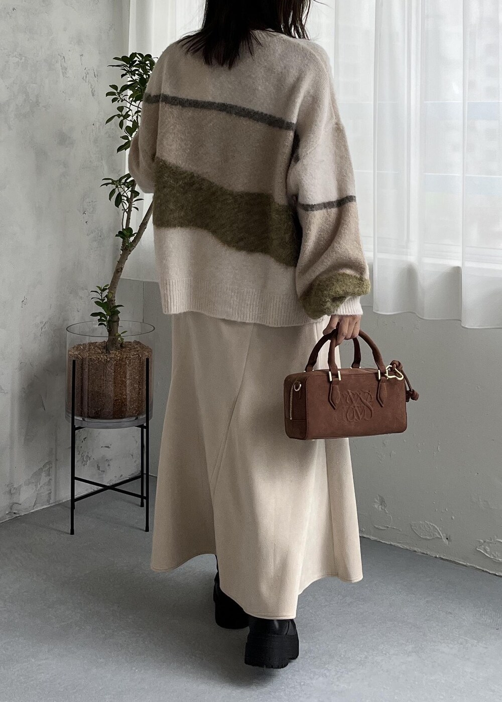 ブラウン系のボストンバッグ、ブラック系のブーツ、ホワイト系のスカートを着用したレディースの秋コーディネートの5枚目の写真