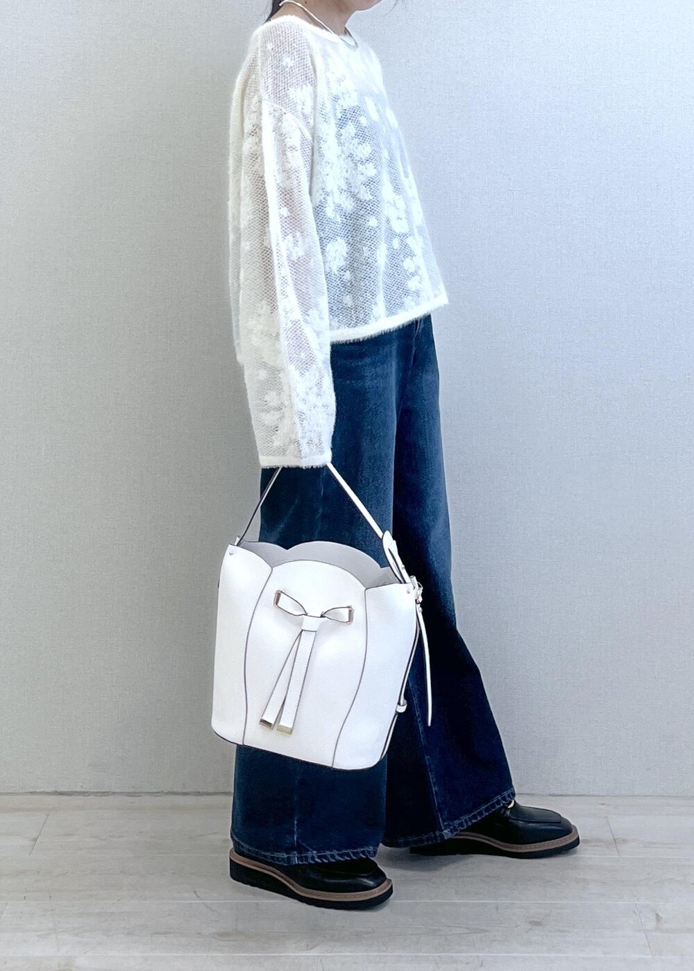 ブラック系のローファー、ホワイト系のニット/セーター、ブルー系のデニムパンツを着用したレディースの秋コーディネートの4枚目の写真