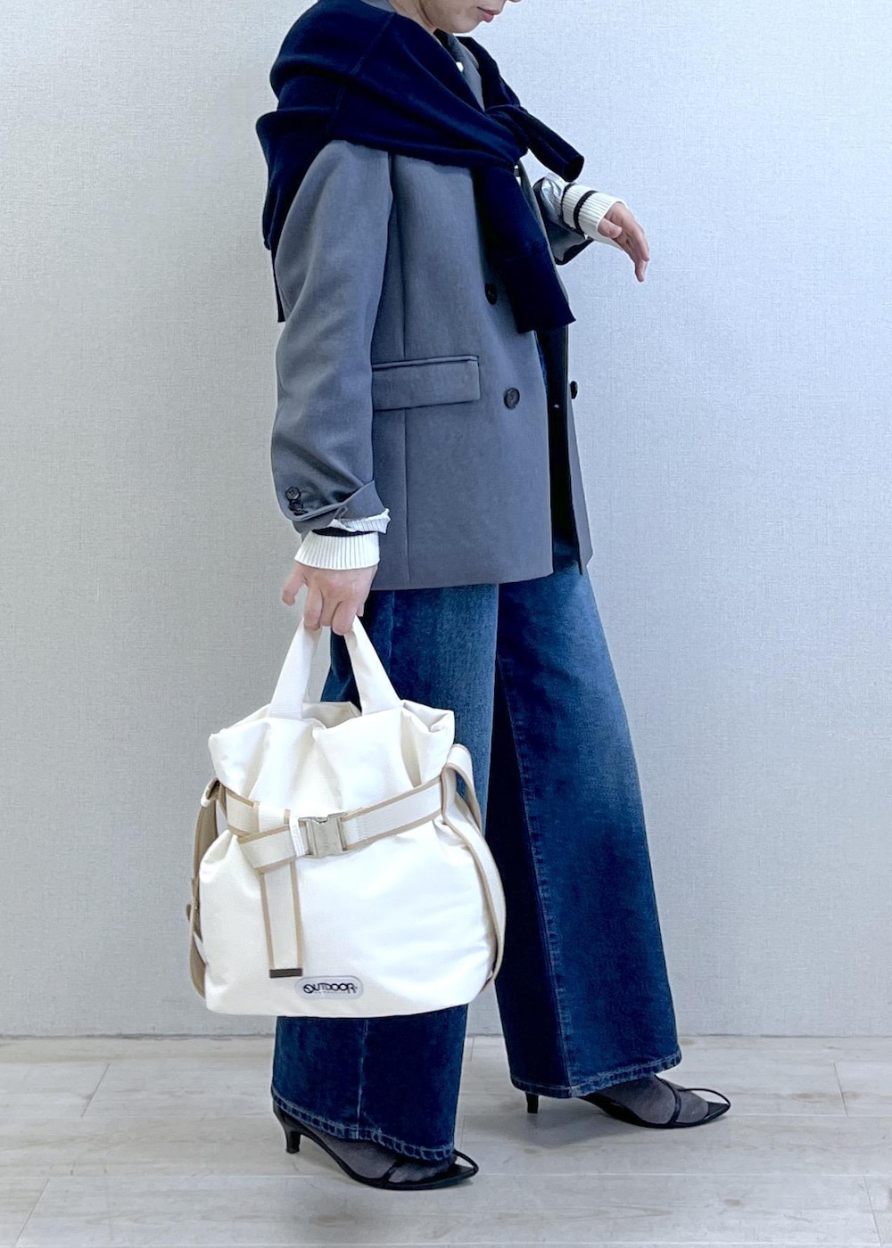 グレー系のテーラードジャケット、ブルー系のデニムパンツ、ホワイト系のニット/セーターを着用したレディースの冬コーディネートの5枚目の写真