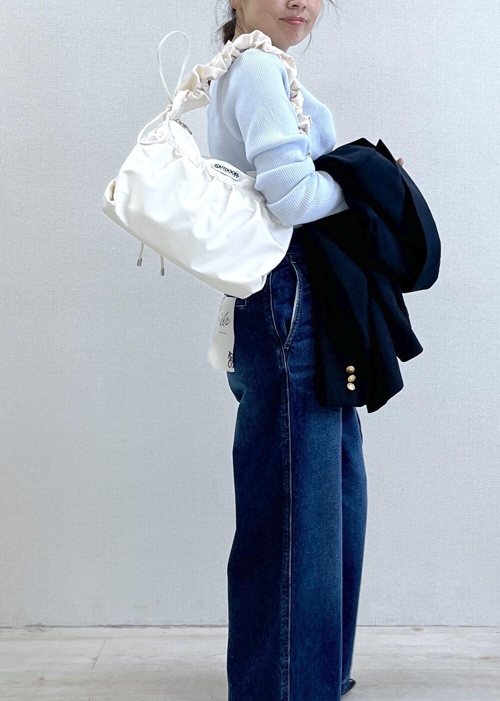 ブルー系のテーラードジャケット、ブルー系のデニムパンツ、ホワイト系のショルダーバッグを着用したレディースの冬コーディネートの7枚目の写真