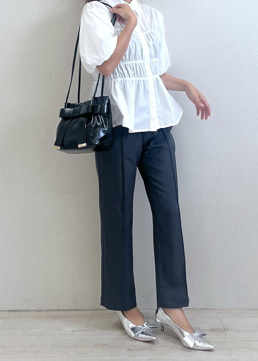 シルバー系のパンプス、ブラック系のショルダーバッグ、グレー系のスラックスを着用したレディースの秋コーディネートの3枚目の写真