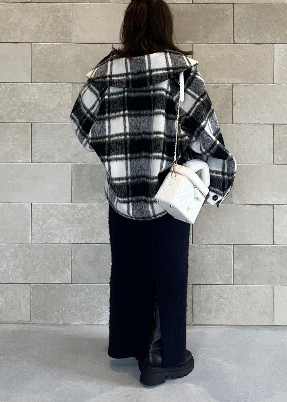 ブラック系のブーツ、ホワイト系のハンドバッグ、ブルー系のスカートを着用したレディースの秋コーディネートの6枚目の写真