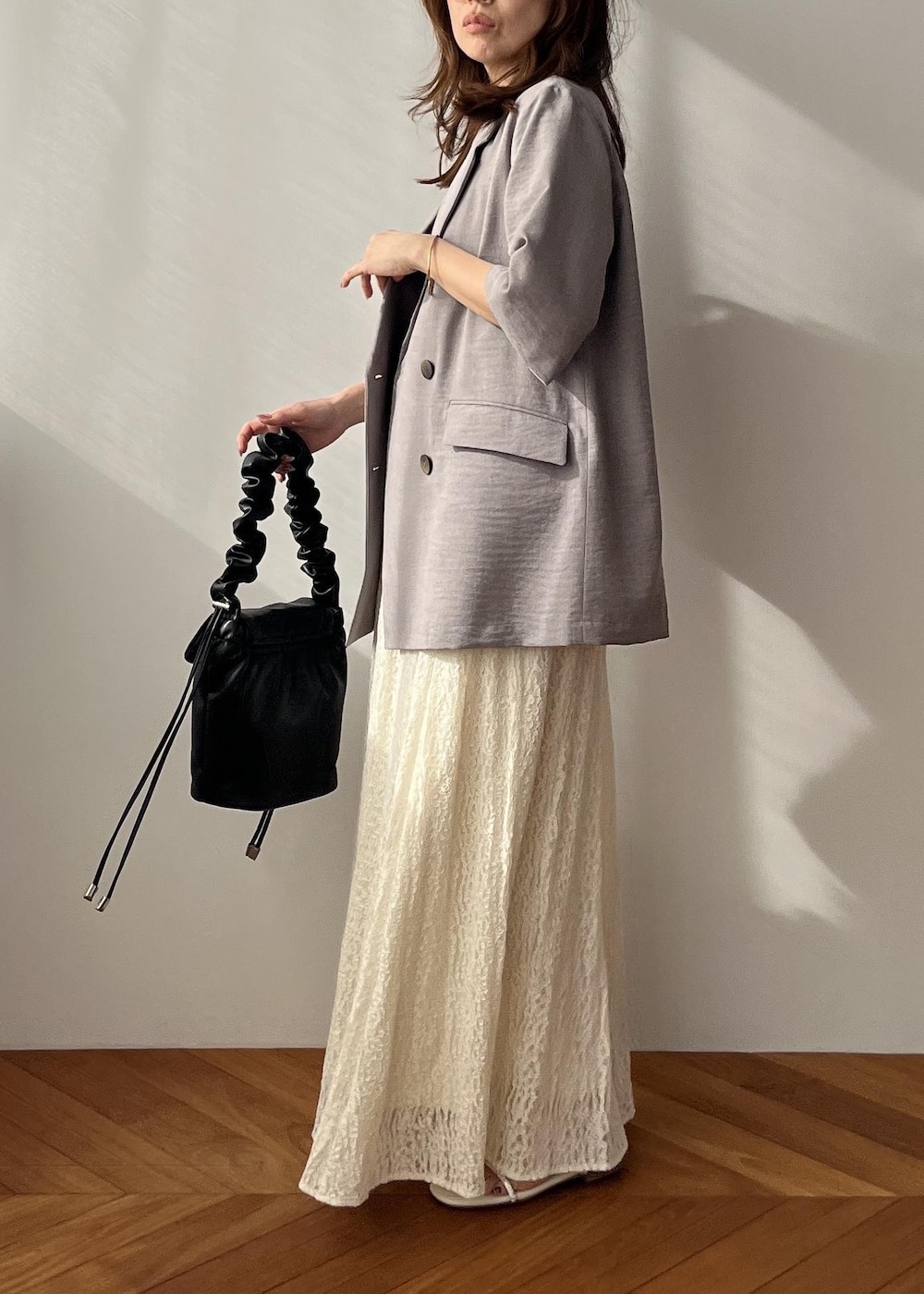 ホワイト系のスカート、ブラック系のショルダーバッグ、ホワイト系のサンダルを着用したレディースの春コーディネートの2枚目の写真