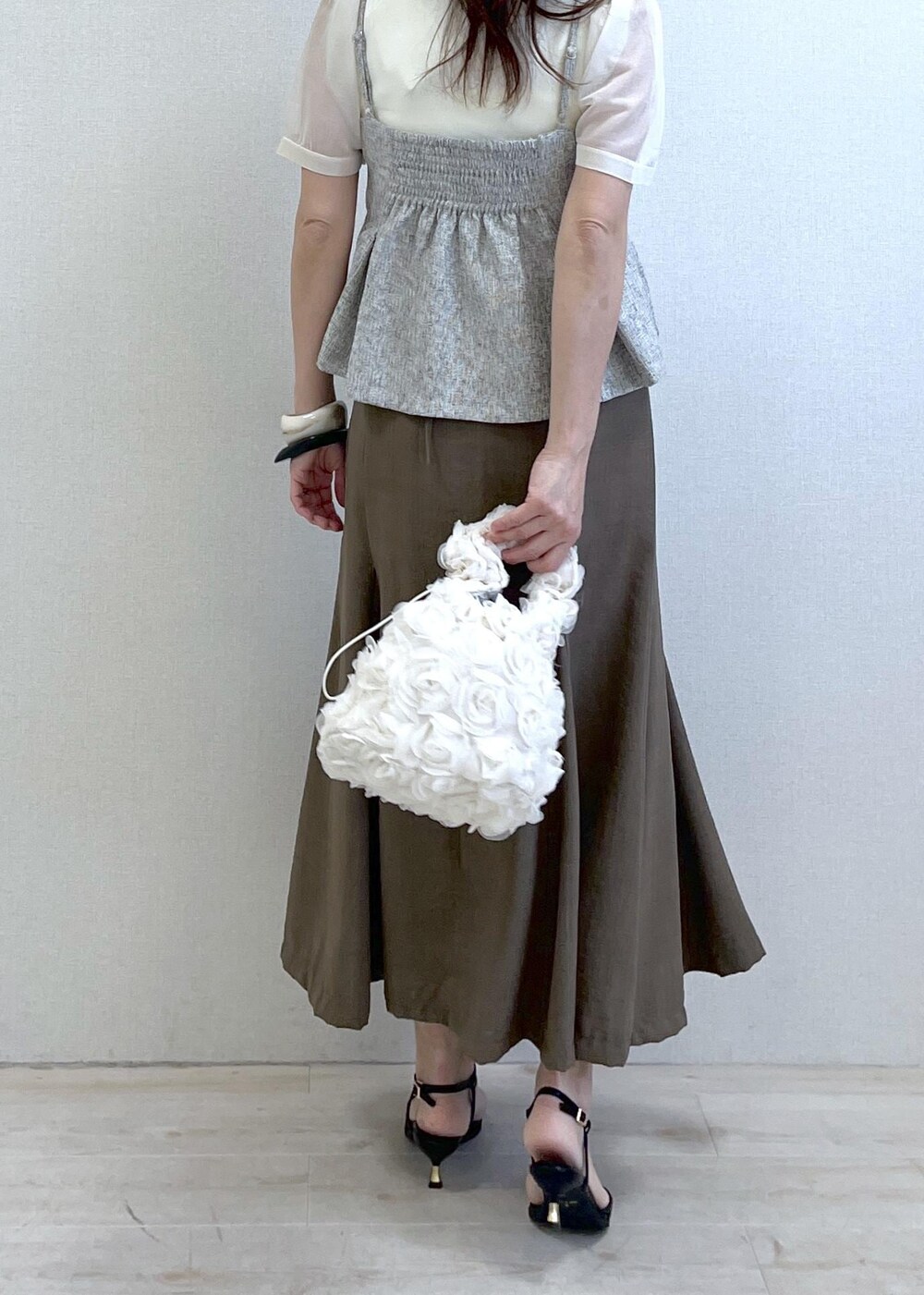 ブラック系のサンダル、ホワイト系のハンドバッグ、グリーン系のスカートを着用したレディースの春コーディネートの4枚目の写真