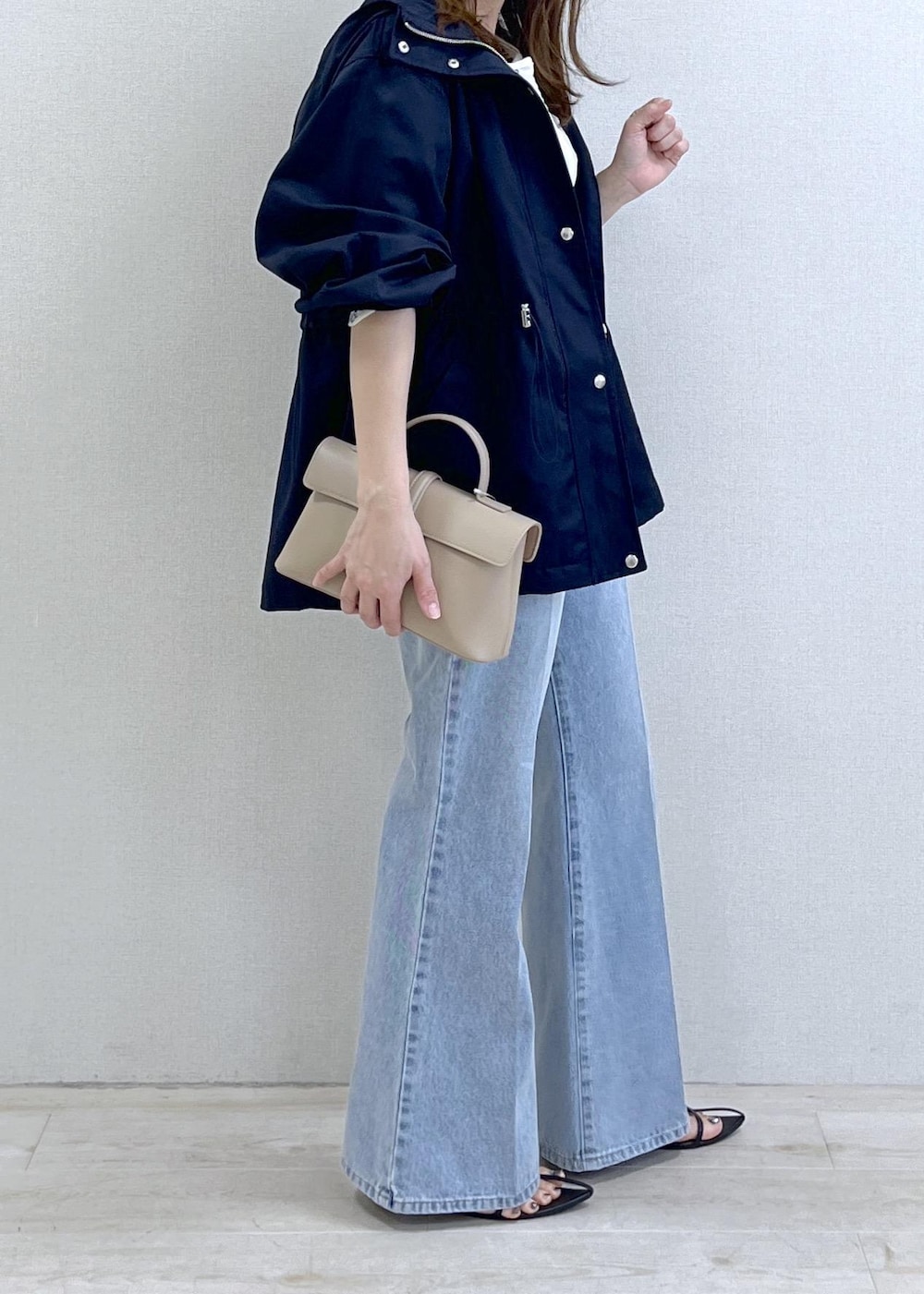 ベージュ系のショルダーバッグ、ブルー系のナイロンジャケット、ブラック系のキャミソールを着用したレディースの春コーディネートの2枚目の写真