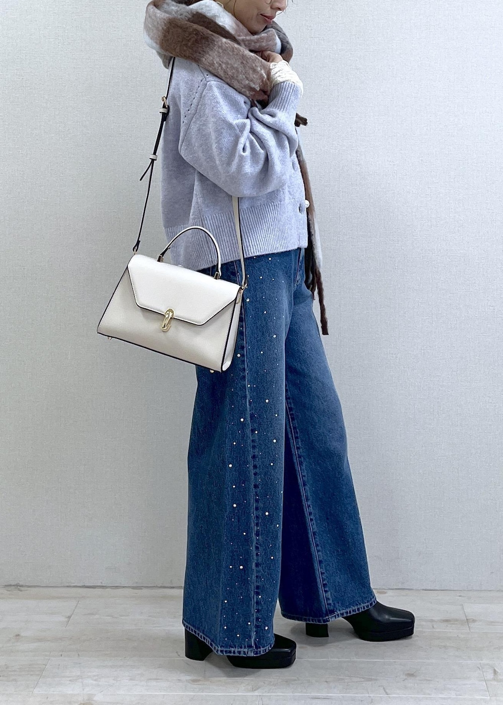 パープル系のカーディガン/ボレロ、ホワイト系のTシャツ/カットソー、ブラック系のブーツを着用したレディースの秋コーディネートの3枚目の写真