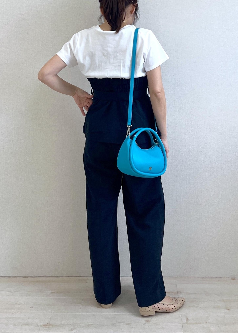 ブルー系のスラックス、ベージュ系のパンプス、ブルー系のショルダーバッグを着用したレディースの春コーディネートの3枚目の写真