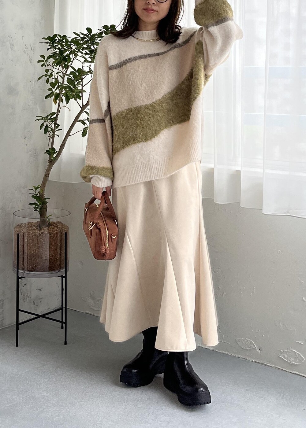 ブラウン系のボストンバッグ、ブラック系のブーツ、ホワイト系のスカートを着用したレディースの秋コーディネートの2枚目の写真