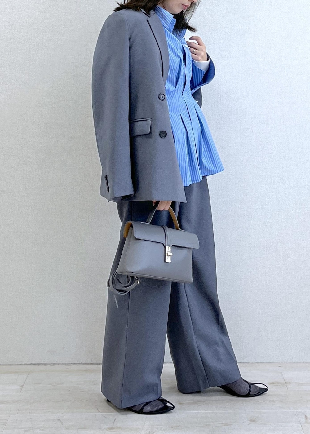 グレー系のショルダーバッグ、ブルー系のシャツ/ブラウス、ホワイト系のニット/セーターを着用したレディースの秋コーディネートの3枚目の写真
