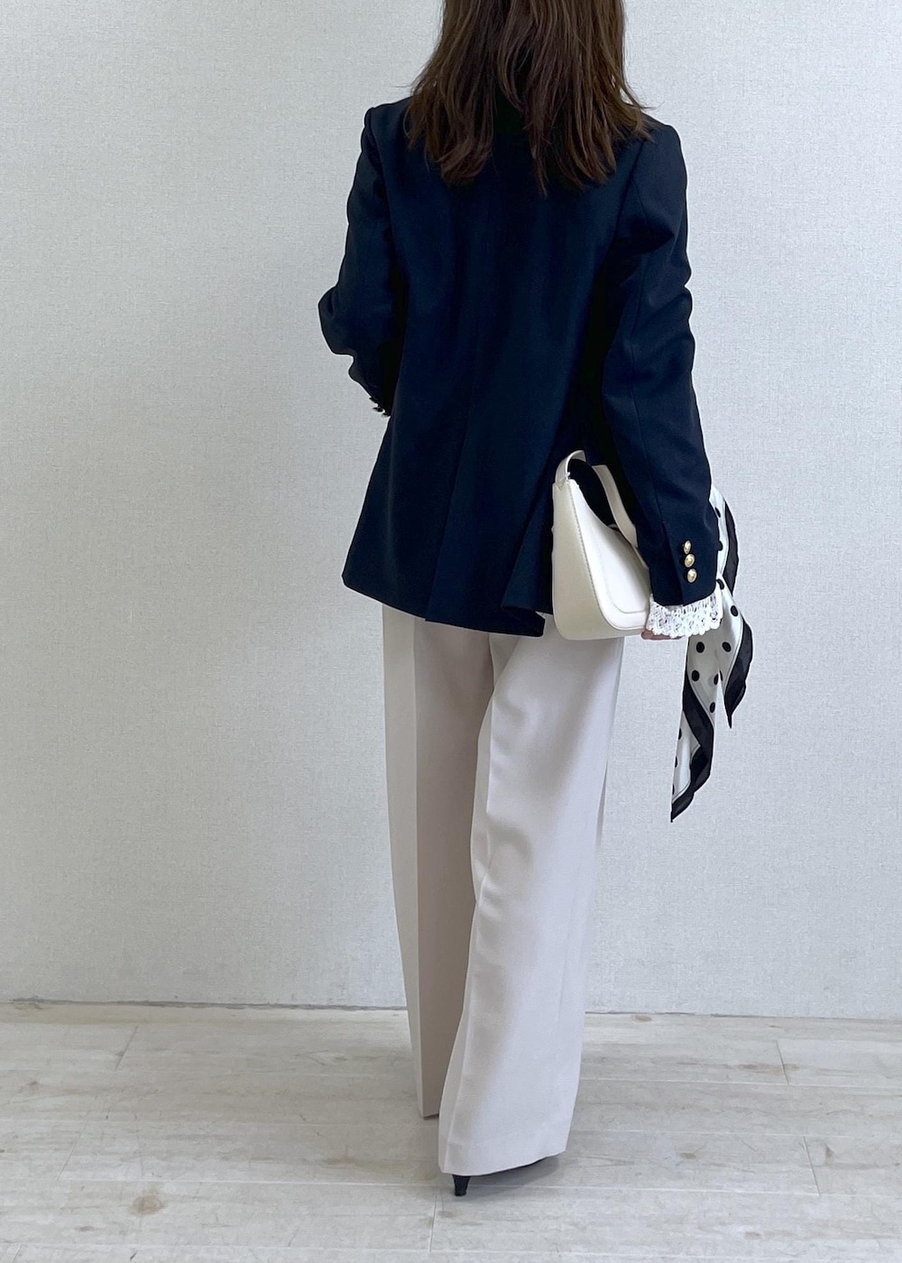 ホワイト系のショルダーバッグ、ブルー系のテーラードジャケット、ベージュ系のその他パンツを着用したレディースの春コーディネートの5枚目の写真