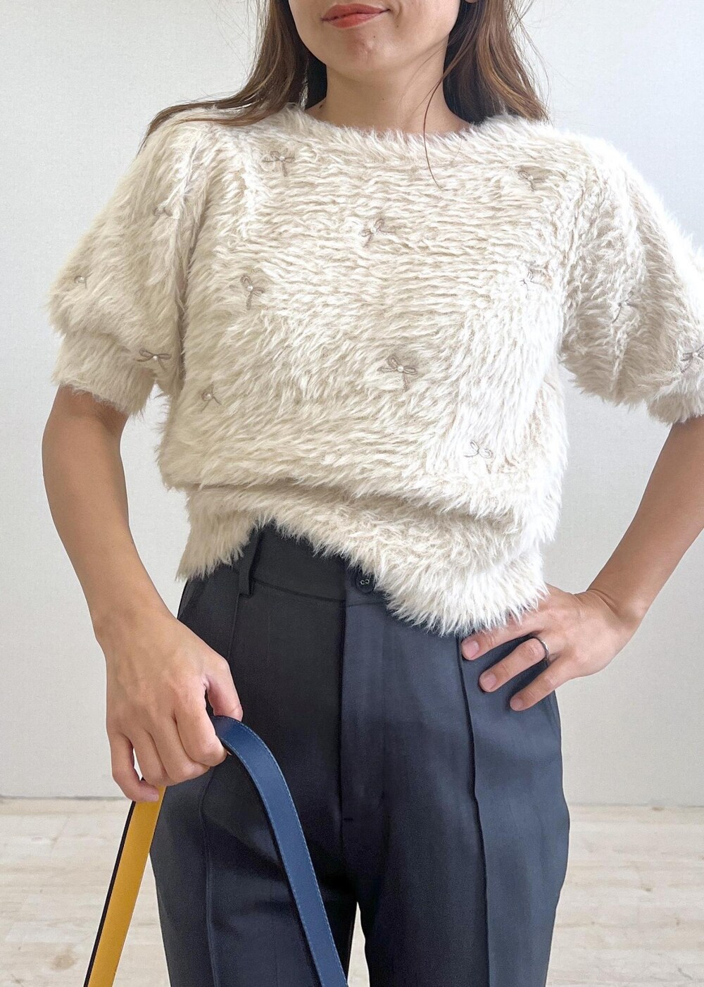 シルバー系のパンプス、イエロー系のショルダーバッグ、ホワイト系のニット/セーターを着用したレディースの秋コーディネートの5枚目の写真