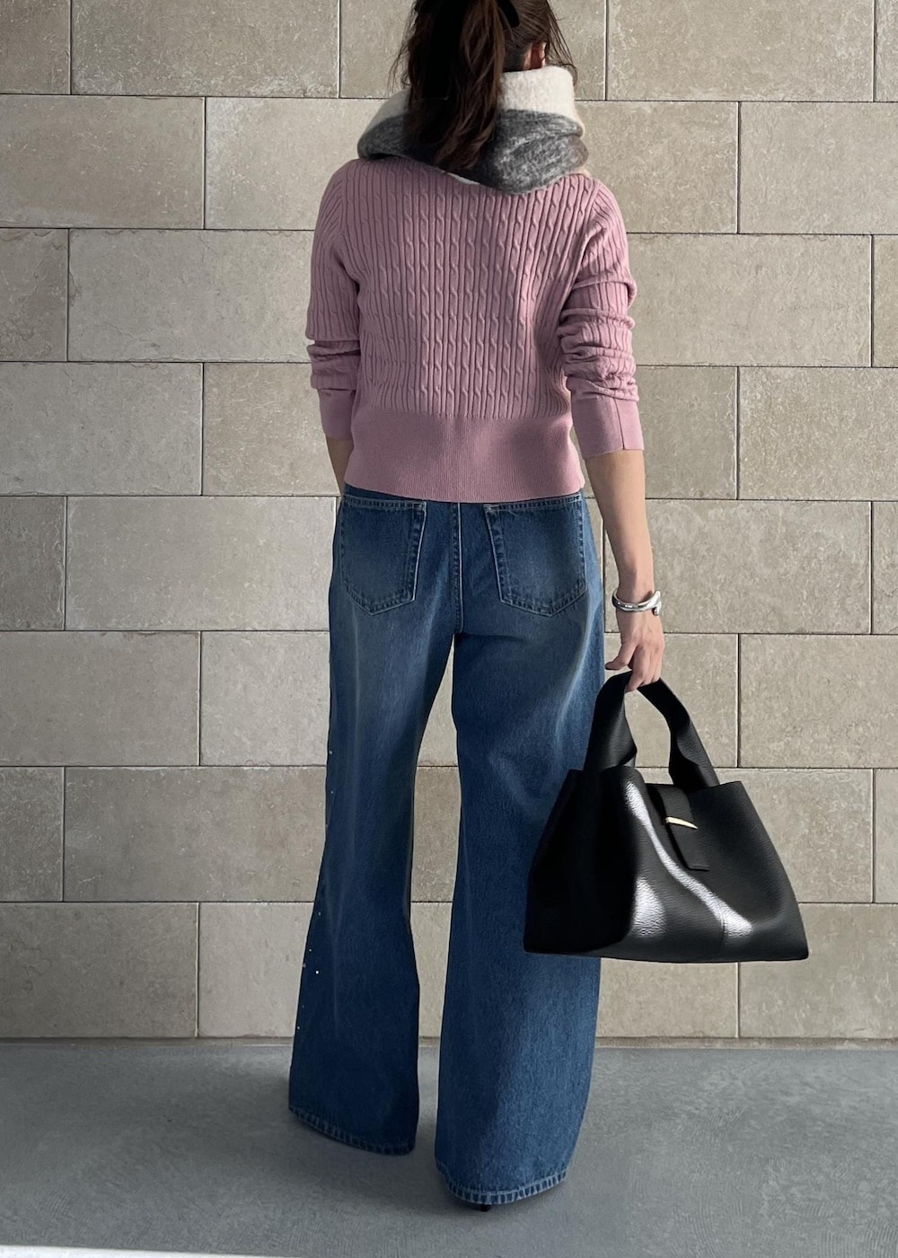 ブラック系のハンドバッグ、ピンク系のカーディガン/ボレロ、ブルー系のデニムパンツを着用したレディースの秋コーディネートの4枚目の写真