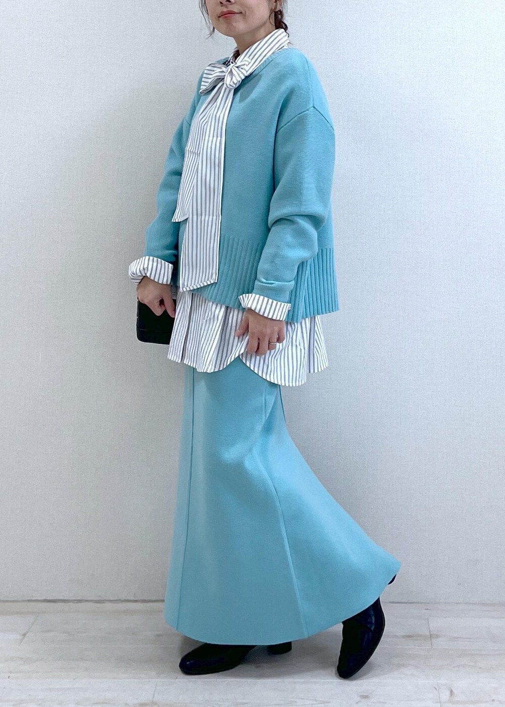 ブラック系のブーツ、ブルー系のスカート、ホワイト系のシャツ/ブラウスを着用したレディースの冬コーディネートの7枚目の写真