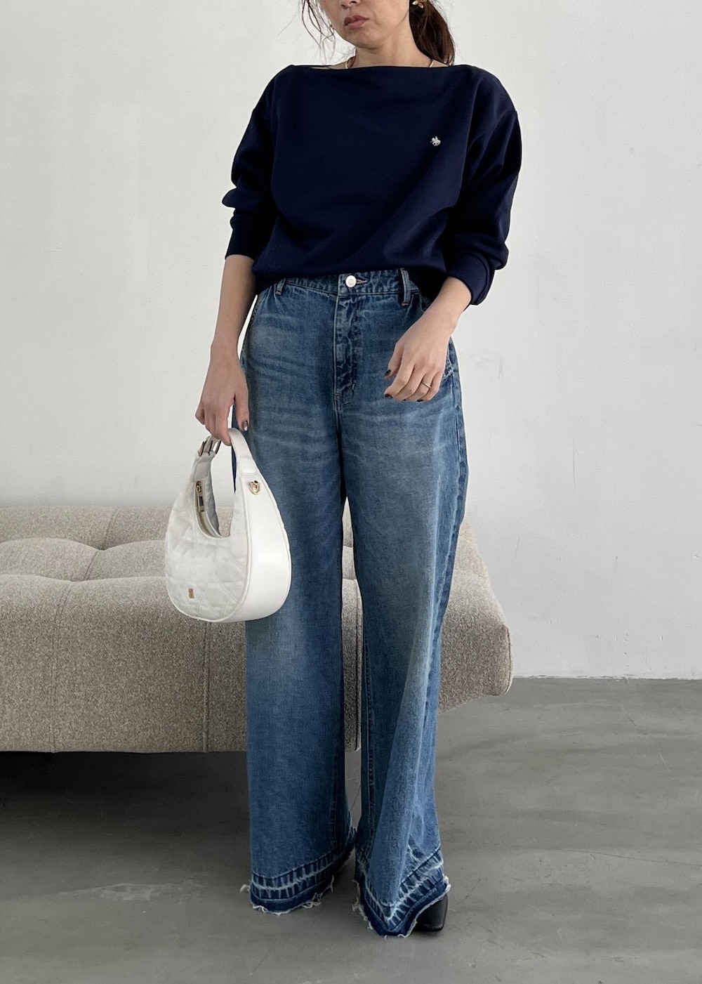 ホワイト系のハンドバッグ、ブラック系のパンプス、ブルー系のデニムパンツを着用したレディースの冬コーディネートの2枚目の写真